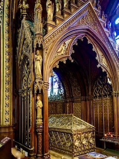 Elaborate Gothic tomb shrine with gilded arches and carved statues inside a Parisian church