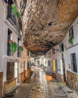 Narrow street with white buildings built under a large overhanging rock in Setenil de las Bodegas, Spain
