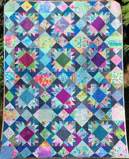 Colorful patchwork quilt with geometric Bearpaws pattern in turquoise, purple, and pink fabrics