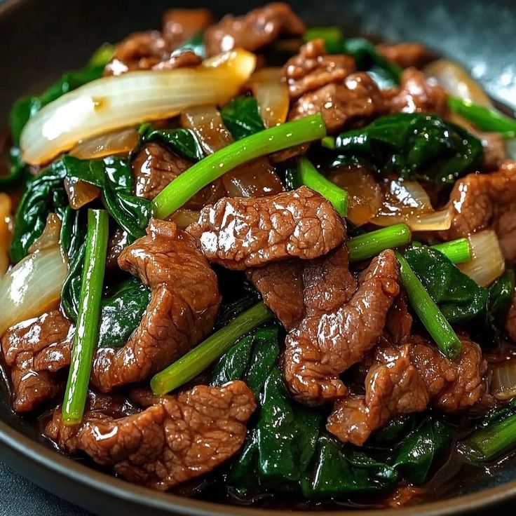 Close-up of beef stir-fry with leafy greens and onion in brown sauce