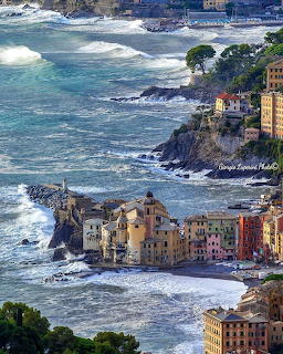 Aerial view of Camogli, Italy with colorful buildings on cliffs overlooking turquoise sea with white waves