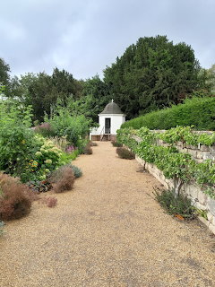 Gravel path through formal garden with cottage and trees