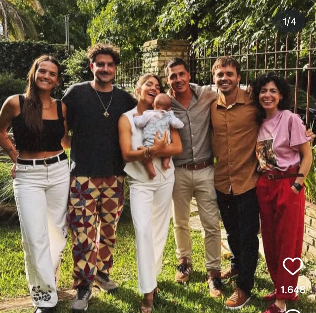 Six people and a baby posing together outdoors on a sunny lawn