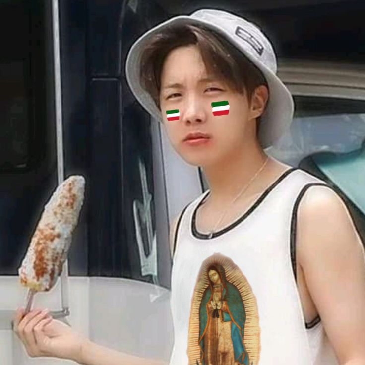 Young person in a bucket hat holding a corn dog, wearing a white sleeveless shirt with face paint stripes
