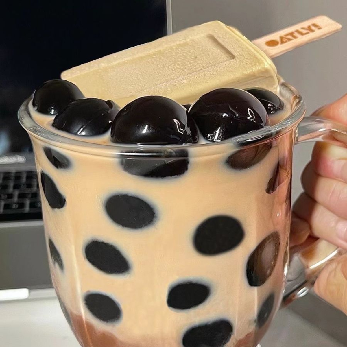 Glass of boba milk tea with tapioca pearls held in hand