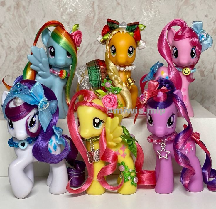Six colorful My Little Pony toy figures posed together on a white surface
