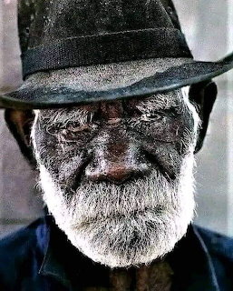 Close-up of an elderly bearded man wearing a dark hat