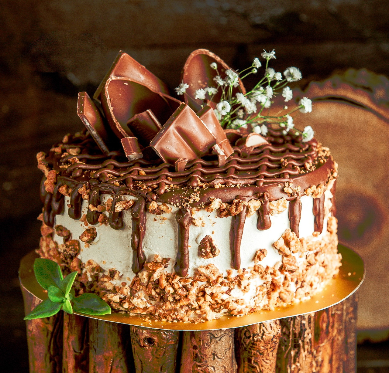 Chocolate layer cake with chocolate curls and white flowers on wooden base