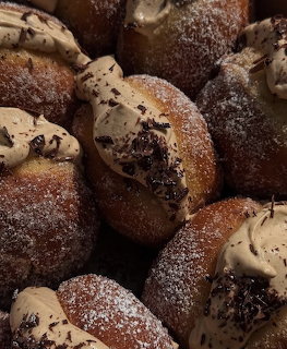 Close-up of sugar-dusted donuts with cream and chocolate chip toppings