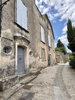 Old stone house with white shutters on cobblestone street in French village