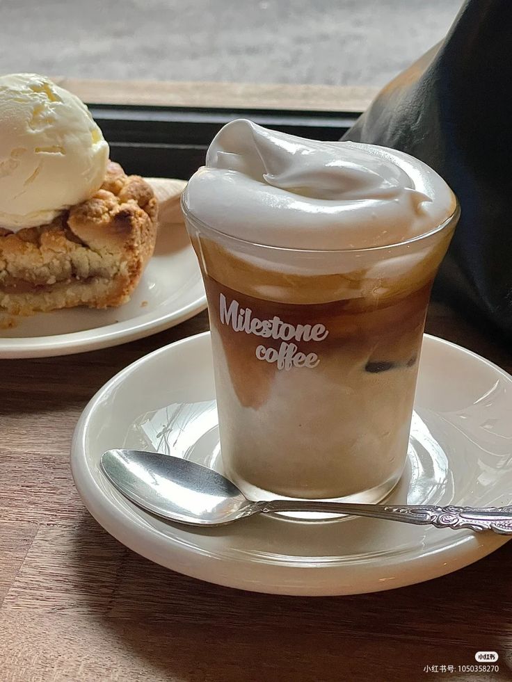 Einspanner coffee with whipped cream in a glass next to apple crumble and ice cream on a wooden table