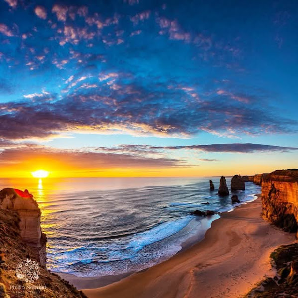 Sunset over ocean beach with dramatic rock formations and colorful sky