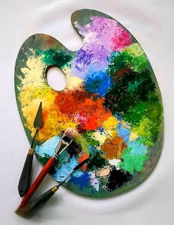 Wooden artist palette with vibrant mixed oil paints and two paintbrushes on white background
