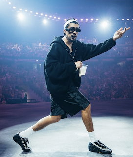 Male performer in sunglasses dancing on a concert stage under bright arena lights