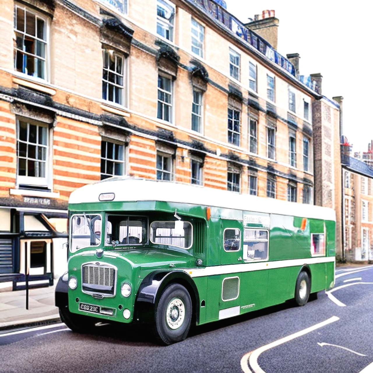 Green vintage Bristol Lodekka double-decker bus on city street with historic buildings