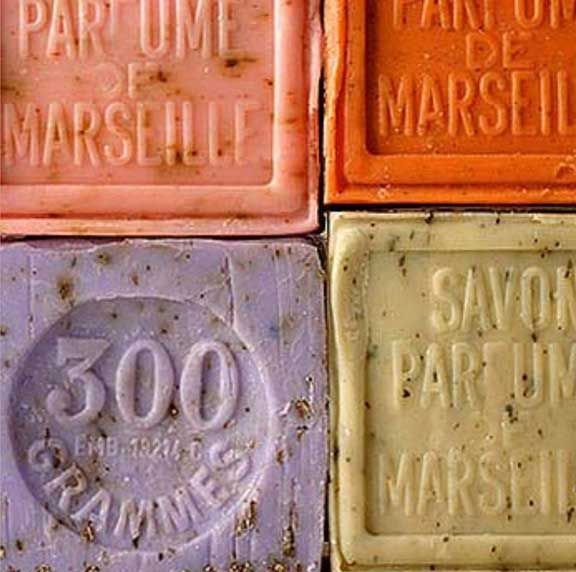 Four vintage Marseille soap bars in pink, orange, purple and yellow with embossed French text