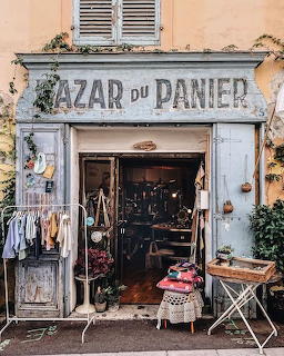 Weathered storefront of Bazar du Panier shop with vintage items and clothing displayed outside
