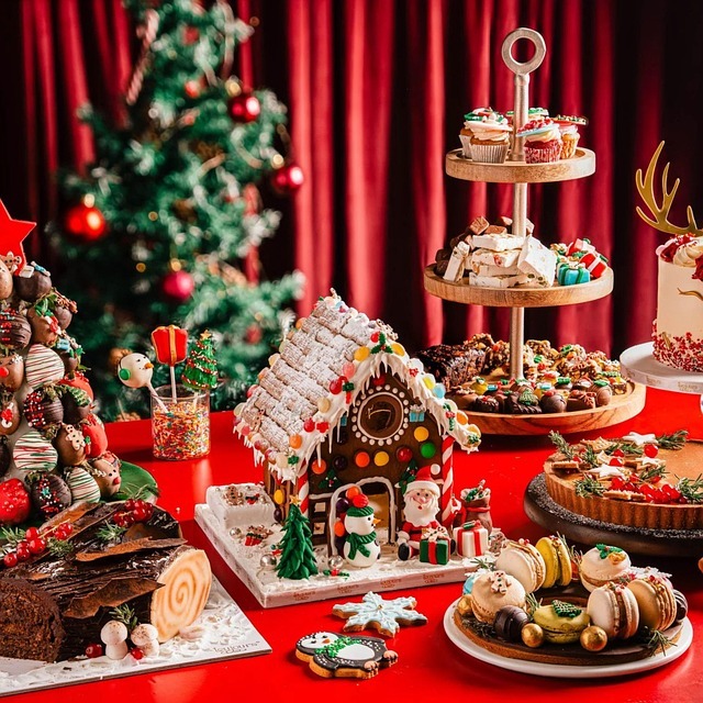 Christmas dessert table with gingerbread house, cookies, macarons, cake rolls and festive decorations