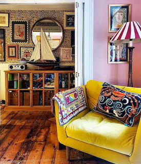 Yellow velvet armchair with vibrant patterned cushions in a colorful eclectic living room