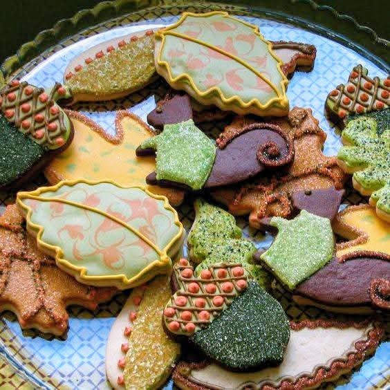 Assorted fall-themed decorated cookies shaped like leaves, acorns and squirrels on a decorative plate