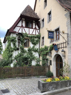 Old half-timbered hotel building with ivy and flowers on a cobblestone street