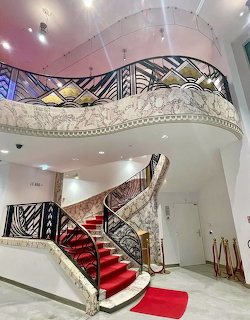 Elegant curved Art Deco staircase with ornate metalwork and red carpet in grand cinema lobby