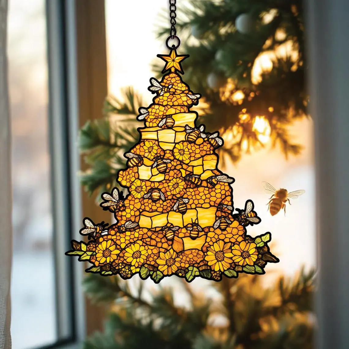 Golden honeycomb Christmas tree suncatcher with bees hanging in window with bokeh lights
