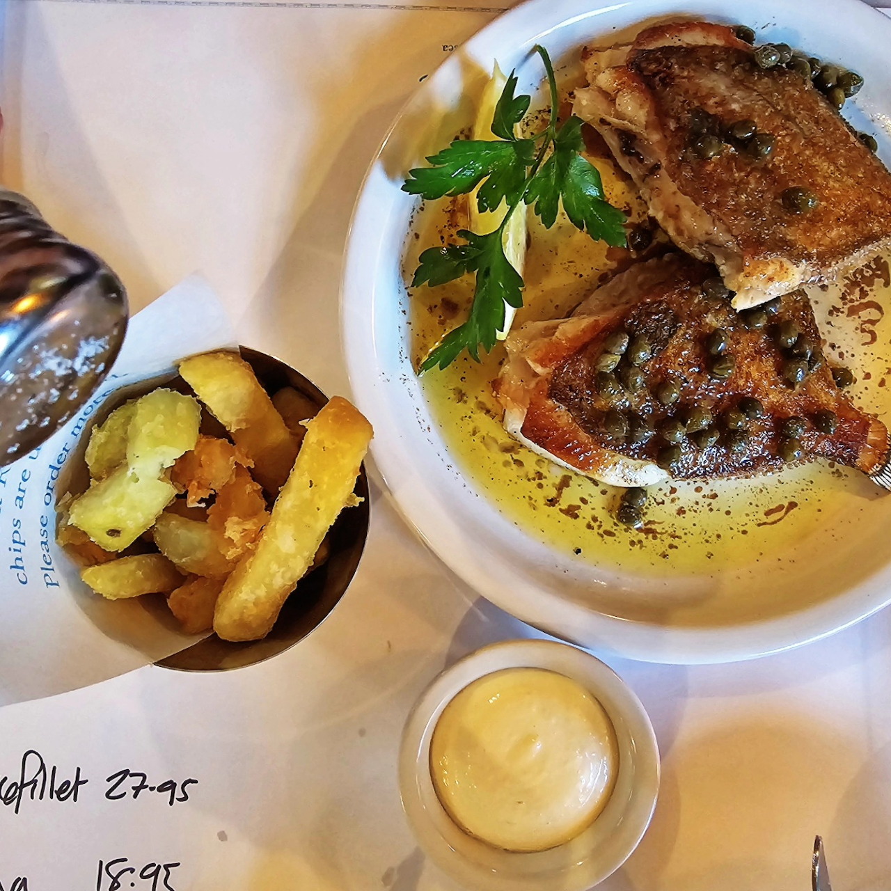 Cooked steak with roasted potatoes, mayonnaise, and herb garnish on a white plate