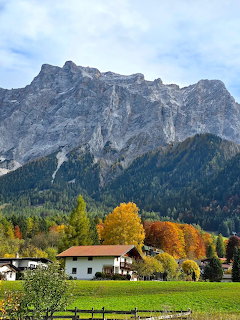 Alpine village with autumn foliage and white houses beneath the towering rocky Zugspitze mountain