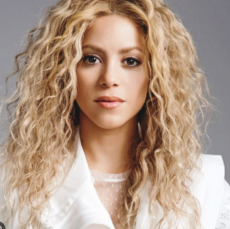 Studio portrait of a blonde woman with long curly hair in a white jacket