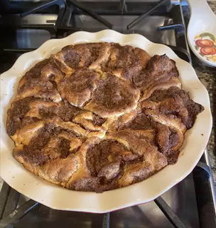 Round pan of baked cinnamon rolls on a stovetop