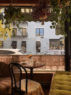 Cafe interior with yellow seating and window view of white buildings with plants