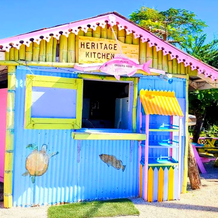 Colorful tropical hut with pastel blue walls, yellow trim, and a Heritage Kitchen sign