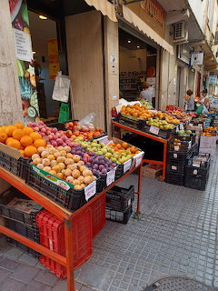 Crates of fresh fruit displayed outside a small street shop on a tiled sidewalk