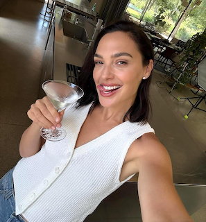 Smiling woman taking an indoor selfie while holding a martini glass