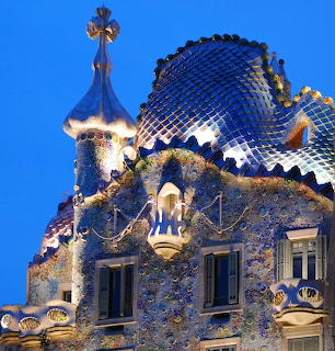 Casa Batlló building in Barcelona with blue mosaic roof, skeletal balconies, and cross-topped tower