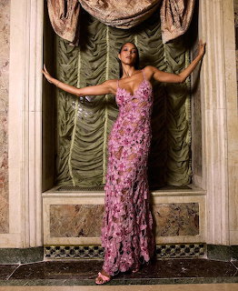 Woman in a pink floral gown posing in an ornate interior alcove