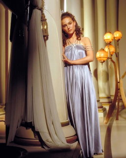Woman in a long silveratin halter gown standing beside draped fabric in an elegant interior