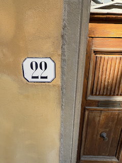Enamel number 22 plate on a yellow wall next to a wooden door