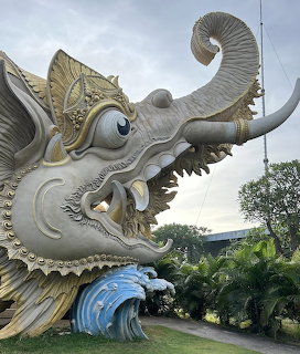 Large ornate mythical dragon sea creature sculpture at Bali harbour with open mouth and wave base