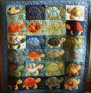 Quilted wall hanging with multicolored turtles in grid pattern on blue background