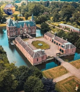 Aerial view of Twickel Castle surrounded by a moat with pink brick buildings and green courtyard