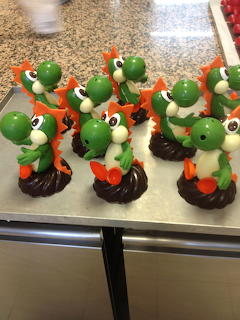 Several green dinosaur-shaped chocolate figures lined up on a metal tray