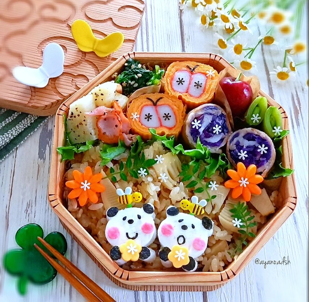 Octagonal bento box with kawaii-style decorated food including character rice balls and carved vegetables