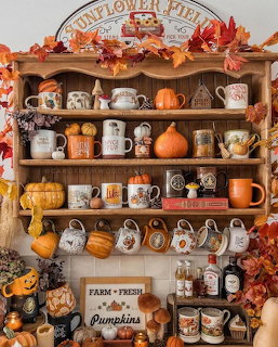 Rustic wooden shelf with autumn decorations, pumpkins, mugs, and fall foliage