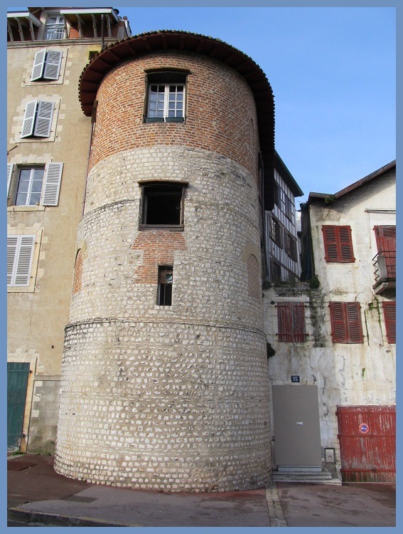 Historic round stone tower beside old buildings in Bayonne