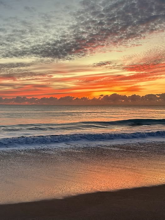 Ocean sunset at a sandy beach with small waves and orange clouds
