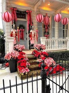 House porch decorated with red poinsettias, nutcrackers, and hanging striped balloon ornaments for Christmas