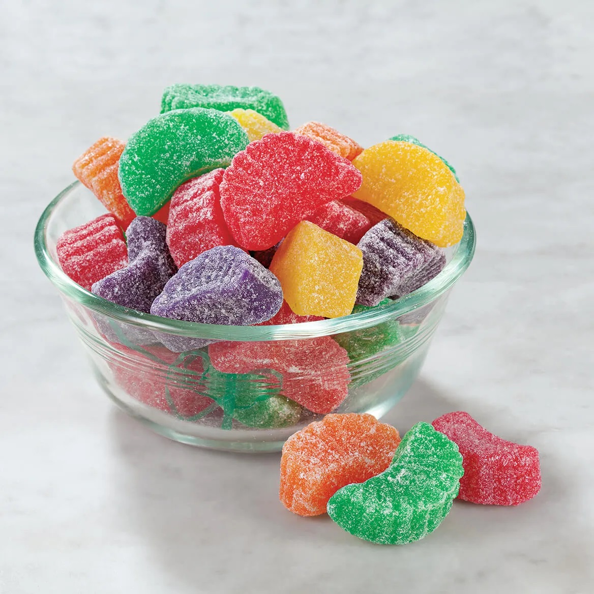 Colorful sugar-coated fruit slice gummy candies in glass bowl