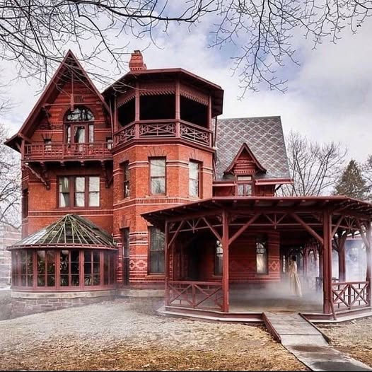 Red brick Victorian mansion with round turret and wooden porch in winter